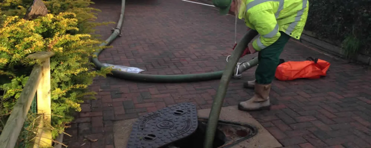 Septic tank cleaning technician servicing a septic tank with a vacuum hose in Tucson, AZ